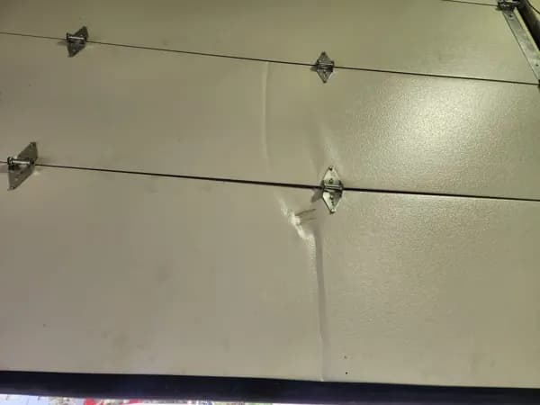 Dented steel garage door panel before replacement