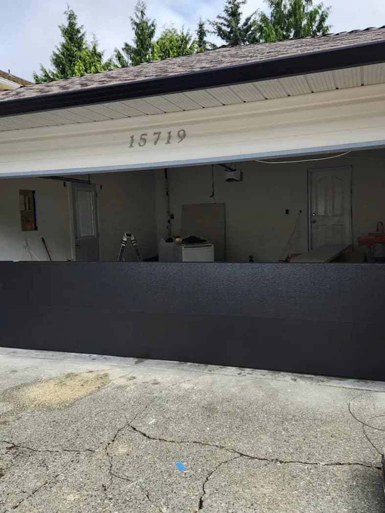 New black insulated steel garage door partway through installation