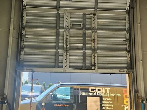 Ribbed steel commercial sectional door from inside, heavy-gauge hinges, vertical struts and a pass door