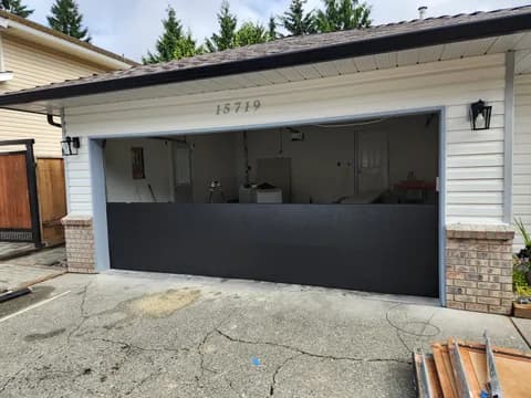 New black insulated steel garage door partway through installation