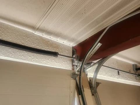 Inside corner of a residential door: torsion spring, flag bracket, end bearing plate, vertical track and the curved radius