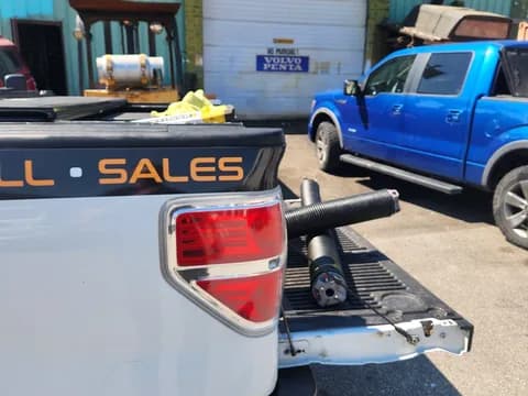 Two new torsion springs with winding cones on the truck tailgate before a spring replacement