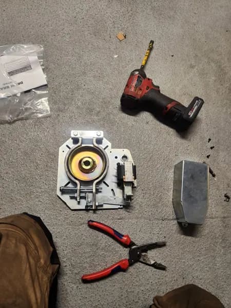 Garage door opener motor and gear parts laid out on a shop floor during a rebuild