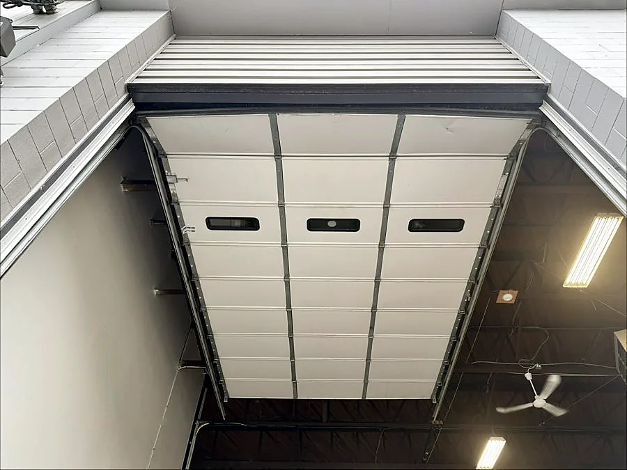 White commercial sectional door open on its tracks — real Up & Down job