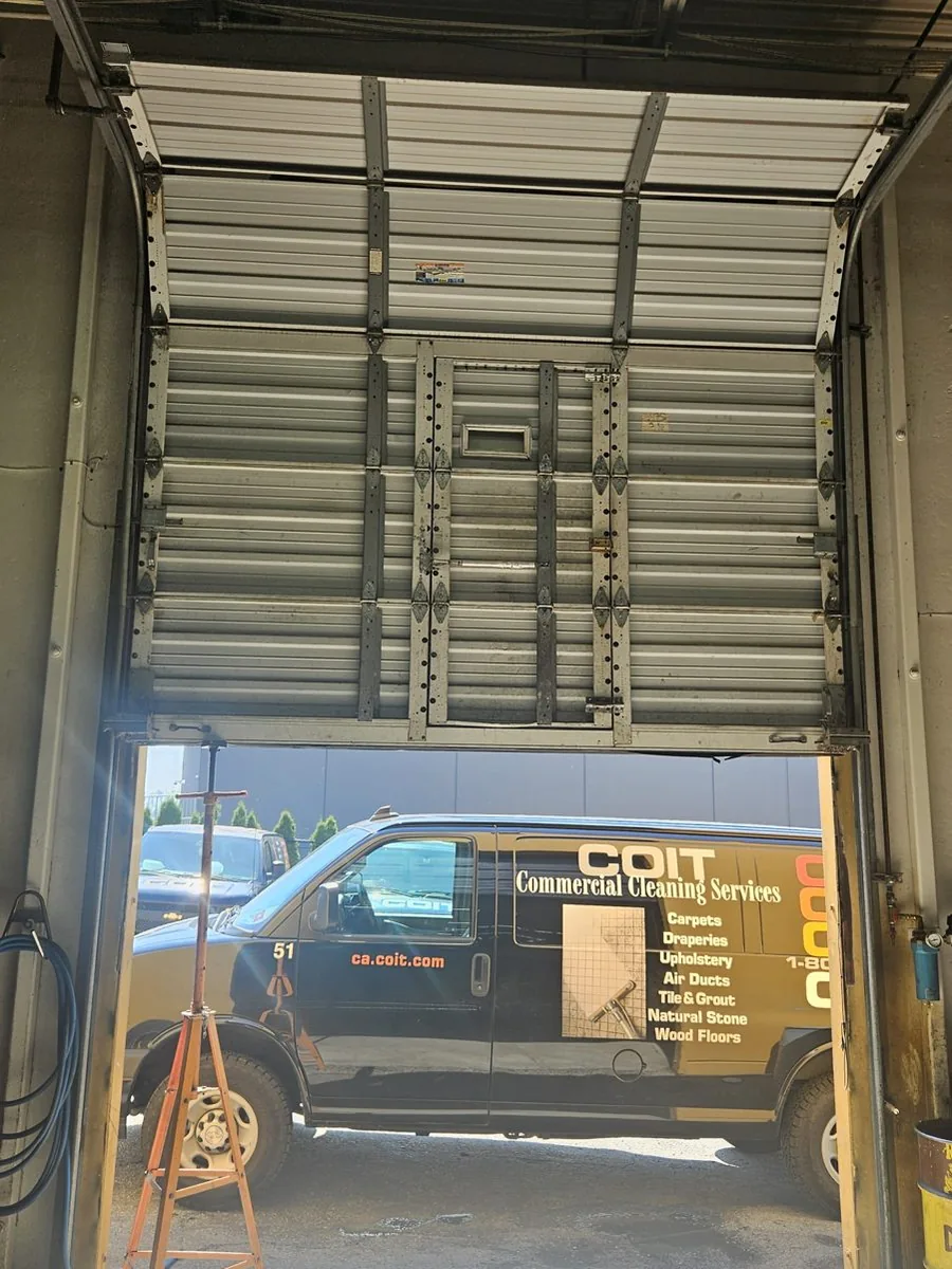 Ribbed steel commercial sectional door from inside, heavy-gauge hinges, vertical struts and a pass door